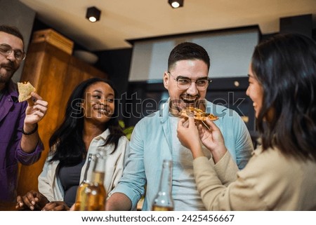 Multi-ethnic friends with pizza and bottles of drinks having party