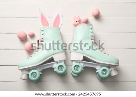 Vintage roller skates with bunny ears made of paper, toy and Easter eggs on white wooden background
