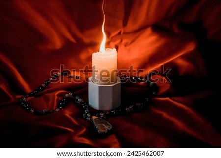 burning candle, a symbol of the moon, an amulet lying on a red natural background. pagan wiccan, slavic traditions. Witchcraft, esoteric spiritual ritual. autumn equinox festival