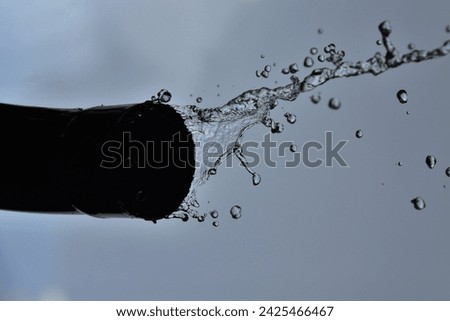 Water flowing through a pipe against blue sky. High speed photography.