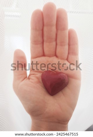 Red chocolate heart in the middle of hand. Heart in hand. Happy valentine's card