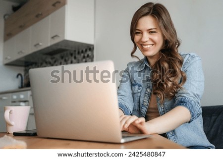 Young woman laughing during video chat at desk. High quality photo