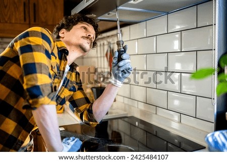 Latino man fixing aspirator in the kitchen. Royalty-Free Stock Photo #2425484107