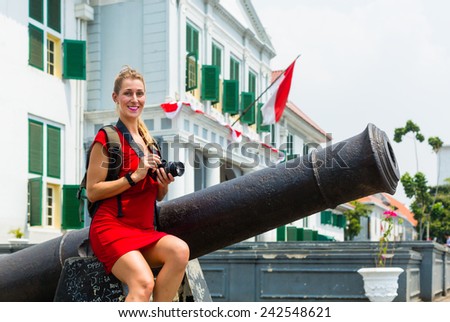 Woman tourist  sitting on cannon in old Batavia colonial district of Jakarta, Indonesia