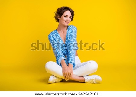 Full size photo of adorable pretty pleasant woman wear blue top white trousers sitting on floor isolated on yellow color background