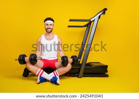 Full size portrait of positive powerful person sit treadmill lifting dumbbells empty space isolated on yellow color background