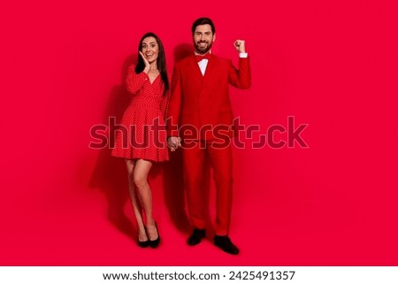 Full size photo of lovely young couple raise fist amazed win valentine day dressed stylish elegant outfit isolated on red color background