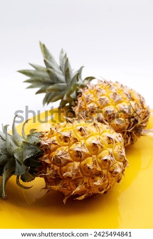 Pineapple fruits placed on yellow plate with white background. Ripe pineapple texture. Fresh fruits for healthy eating, sour and sweet for making smoothines. Close-up pineapple image with copy space.