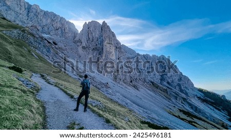 Hiker man with panoramic view of majestic mountain cliff Schartenspitze in untamed Hochschwab mountain region, Styria, Austria. Scenic hiking trail in remote Austrian Alps. Wanderlust, alpine summer Royalty-Free Stock Photo #2425496181
