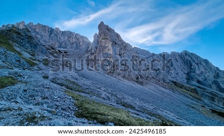 Panoramic view of majestic mountain cliff Schartenspitze in untamed Hochschwab mountain region, Styria, Austria. Scenic hiking trail in shadows in remote Austrian Alps. Wanderlust in alpine summer Royalty-Free Stock Photo #2425496185