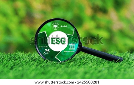 Magnifying glass focused on ESG text with picture smart icon on green grass in nature garden background, choosing environmental concept.Enhance ESG alignment.