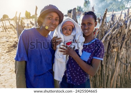 village, african teenager sisters and baby, standing in the yard, golden hour sunset Royalty-Free Stock Photo #2425504665