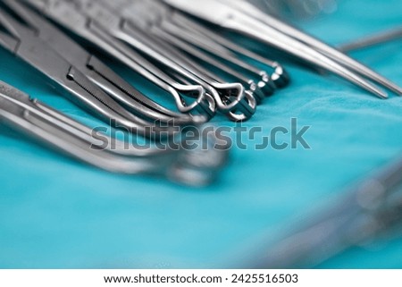 surgical instruments and tools including scalpels, forceps and tweezers arranged on a table for a surgery, Sterilized surgical instruments on the blue wrap Royalty-Free Stock Photo #2425516503