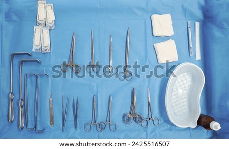 surgical instruments and tools including scalpels, forceps and tweezers arranged on a table for a surgery, Sterilized surgical instruments on the blue wrap Royalty-Free Stock Photo #2425516507