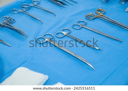 surgical instruments and tools including scalpels, forceps and tweezers arranged on a table for a surgery, Sterilized surgical instruments on the blue wrap Royalty-Free Stock Photo #2425516511