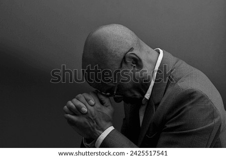 black man praying to god with black grey background with people stock image stock photo	