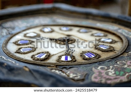 Antique clock with ornate hands and Roman numerals. The weathered metal frame showcases intricate design. Craftsmanship evident in the time-worn, detailed features. Royalty-Free Stock Photo #2425518479
