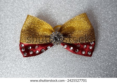 on a silver shiny background lie a red and gold bow decorated with stones. hair accessories. for dogs. top notes. view from above . for pets. Christmas
