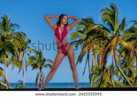 In the enchanting Caribbean, a radiant woman strikes a pose on a stunning beach, her silhouette graced by the vivid blue sky, embodying timeless beauty and coastal allure. Royalty-Free Stock Photo #2425535995