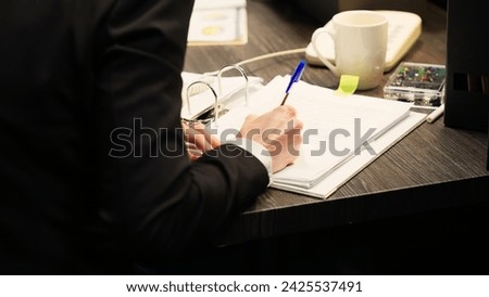 Police agent using landline phone, answering call and taking notes to evaluate evidence authenticity in incident room. Investigators team working on case with classified documents. Handheld shot. Royalty-Free Stock Photo #2425537491