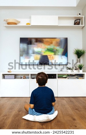 Boy watching television alone in a living room.