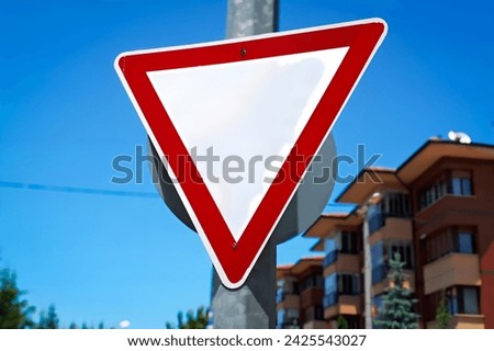 Yield Sign in Urban Setting - Clear Blue Sky and Modern Architecture Background, City Traffic and Safety Concept with a Yield Sign and Residential Buildings