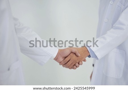 Healthcare professional and scientist in white lab coat shaking hand on white background. Closeup Royalty-Free Stock Photo #2425545999