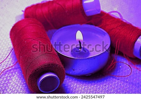 A burning candle, sewing threads on textiles.