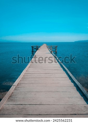 Wooden pier with a backdrop of blue sky and blue sea on Lembata Island, East Nusa Tenggara.