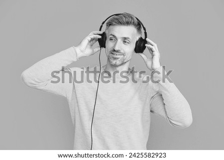 photo of smiling man listen music in headphones. man listen music in headphones isolated on blue