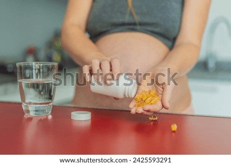 pregnant woman conscientiously takes fish oil capsules, rich in omega-3, prioritizing essential nutrients for a healthy pregnancy journey Royalty-Free Stock Photo #2425593291