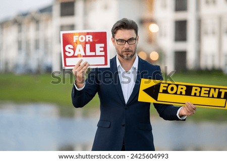 Realtor agent is a realtor with sign for sale and for rent in hand against the background on new apartment home background. Realtor offering new home. Property rent vs sale.