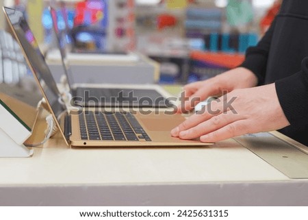 A young man's hands on the keyboard of an exhibition sample laptop. Buyer checking laptops in a computer store