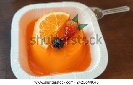 Picture close up an orange cake with strawberries and oranges on the cake.