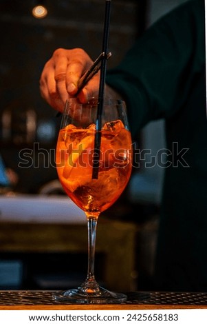 Realistic photo, close-up view of professional bartender in bar making cocktail in a tall glass, with ice and alcohol, male hands in picture