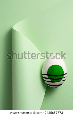 Green painted easter egg on green curled paper background