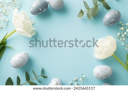 Seasonal elegance in a picture of slate grey eggs, alongside gypsophila, eucalyptus and tulips arranged on a pastel blue canvas, leaving margin for messages
