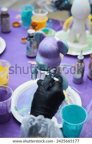 We water the plaster figurine of the bear with paints of various colors. Creativity for children.