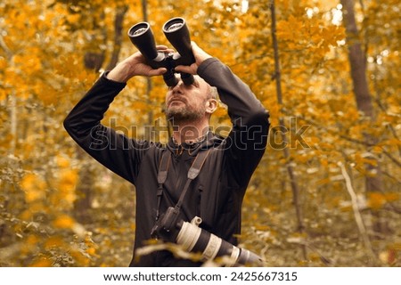 Man using binoculars for birdwatching and other observing animals in nature. Royalty-Free Stock Photo #2425667315