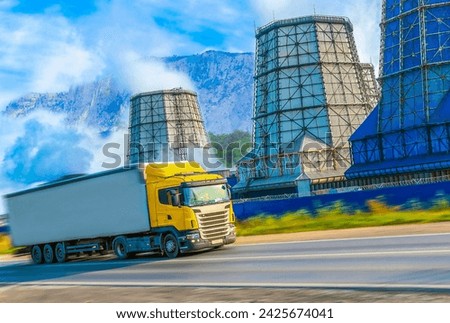 Metallurgical plant pipes. Yellow truck in soft focus with motion blur effect rushes along the highway. Freight transportation of metal, delivery products by road. Industrial auto transport.