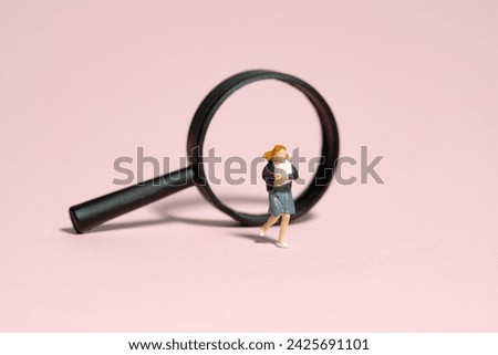 Miniature people toy figure photography. A girl pupil student running in front of magnifier glass. Isolated on pink background. Image photo