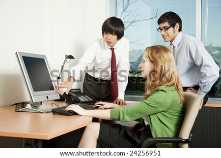 Three business colleagues analyzing data on computer screen