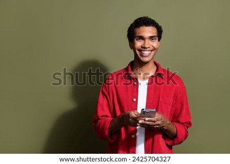 Photo of good mood cool guy wear red shirt texting instagram twitter telegram facebook empty space isolated khaki color background