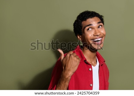 Photo of cool funky man dressed red shirt showing thumb back looking empty space isolated green color background
