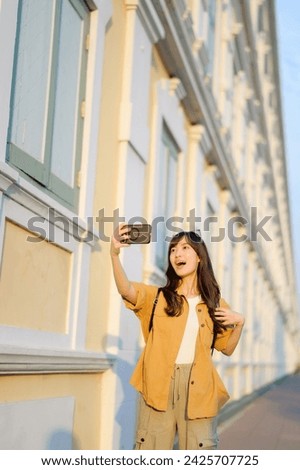 Traveler asian woman 30s making a livestream and sefie with a smartphone enjoying travel in Bangkok, Thailand. Journey trip lifestyle, world travel explorer or Asia summer tourism concept.