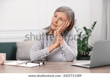 Menopause, mood changes. Sad woman at wooden table indoors Royalty-Free Stock Photo #2425711589