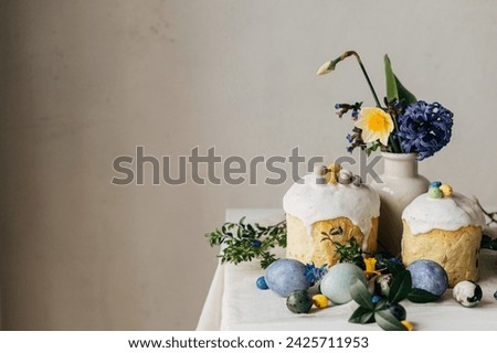 Stylish easter eggs, panettone, spring flowers and chocolate eggs on rustic wooden table. Natural dye marble eggs, blossom and holiday food. Space for text. Happy Easter!