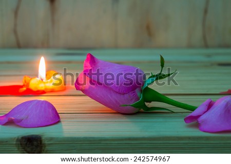 still life with candle and rose flower on wooden table over grunge background, Valentine concept.