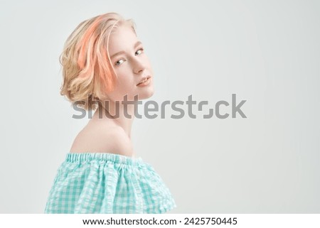Delicate spring-summer look. A cute blonde teenage girl with a short haircut in a summer sundress poses against a white wall. Beauty, cosmetics. Copy space.