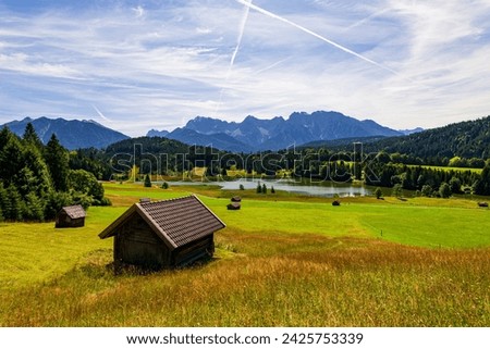 Meadow with small huts and Geroldsee (´Gerold lake) in Bavarian Alps, Germany. Sunny day in majestic Alps Royalty-Free Stock Photo #2425753339